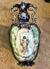 544 or 5LL marked  on base of two handled ornate vase/urn with painted panel of angel on a swing on blue ground