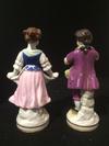 A Pair of Boy Girl Figurines with a 3 loops crown mark with a cross on top and two Gs one a backtofront mirror G