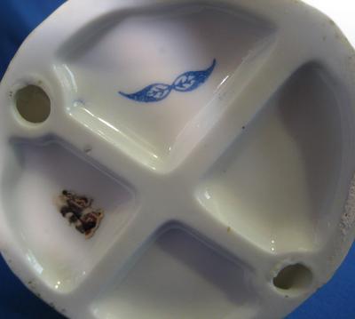 Two blue feathers mark of a pair of seated figurines, or possibly leaves conjoined at the stem